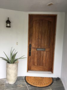 A close-up shot of the wooden door and door mat